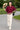 Model holding hat in merlot button-down scallop hem shirt with cream skirt, city park, afternoon light.