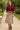 Woman posing in colorblock button-down shirt with scallop hem, beige skirt, park path, daylight.