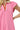 Close-up of pink fabric and bold red-white trim on sleeve and neckline