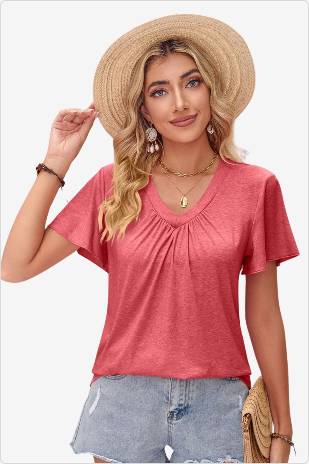 Woman in coral top with a chic straw hat, epitomizing casual summer elegance.