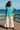 Standing on pier in cotton gauze shirt with wide-leg pants and sandals, ocean breeze midday