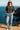 Woman in ash black oversized t-shirt, denim mini skirt and white sneakers, walking on coastal path at sunset