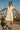 Person wearing a beige dress with blue trim on a rooftop with cityscape in the background