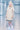Person wearing a beige dress with navy trim and white sneakers in a futuristic hallway.