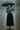 African American model in denim crop top with black tiered skirt and umbrella on rainy street