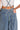 Close-up view of medium wash cotton denim fabric with stitched pocket detail.