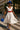 White midi dress styled with red belt, cobalt hat, and heels for chic city look