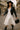 White midi dress with black boots and leather jacket styled for edgy fall streetwear