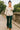 Woman walking across stone bridge in Fitted Linen Blend Shirt with Ribbon Embroidery Color: OATMEAL, natural light.