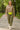 Woman walking in cocoa fleece cropped zip hoodie with cargo joggers and neon belt bag, city park morning.