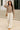 Model walking in cocoa fleece cropped zip hoodie with wide-leg cream pants and tan loafers, city steps evening.