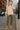 Standing in oversized fleece sweatshirt with cargo pants and tan boots, cobblestone street, city daylight
