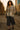 Walking on urban alley in floral-patch denim jacket, navy culottes and combat boots, sunset glow