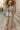 Standing on museum steps in floral-patch denim jacket with culottes and strappy sandals, morning sun