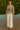 Woman in floral blouse and wide-leg ivory trousers on dock during golden hour