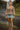 Woman in peplum blouse and denim mini skirt with suede boots by waterfall trail