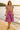 Strolling on lakeside sand in floral puff sleeve blouse with purple tiered skirt, barefoot, golden hour glow