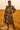 Woman in a patterned dress standing in a field at sunset