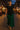Woman walking at night market in black flowy round hem rayon t-shirt with green trousers and sandals, evening lights.