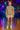 Woman in French Terry Hoodie with metallic pleated skirt and roller skates, under neon rink lights