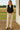 Woman standing in Heart Quilted Vest with beige jeans and boots, on wooden porch, sunny day