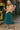 White model in jacquard knit hoodie and teal skirt with silver rain boots outside retro arcade