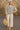 Woman in heather gray jacket and pants standing in front of a stone archway