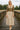 Woman standing in Ribbed Knit Top with floral skirt and ankle boots, on bridge, cloudy sky