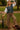 Woman in midnight blue knit vest, white blouse, plaid trousers, and brown shoes, holding umbrella in park