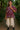 Female smiling in Mix Paisley Boho Tunic Blouse Color: Wine Mix with lace ruffle pants, indoor garden.