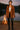 Woman in Mocha suede blazer with fringe, leather pants and boots, by campfire near lake, evening light