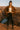 Woman in Mocha suede blazer with fringe, leather pants and boots, standing on canyon edge, sunset light