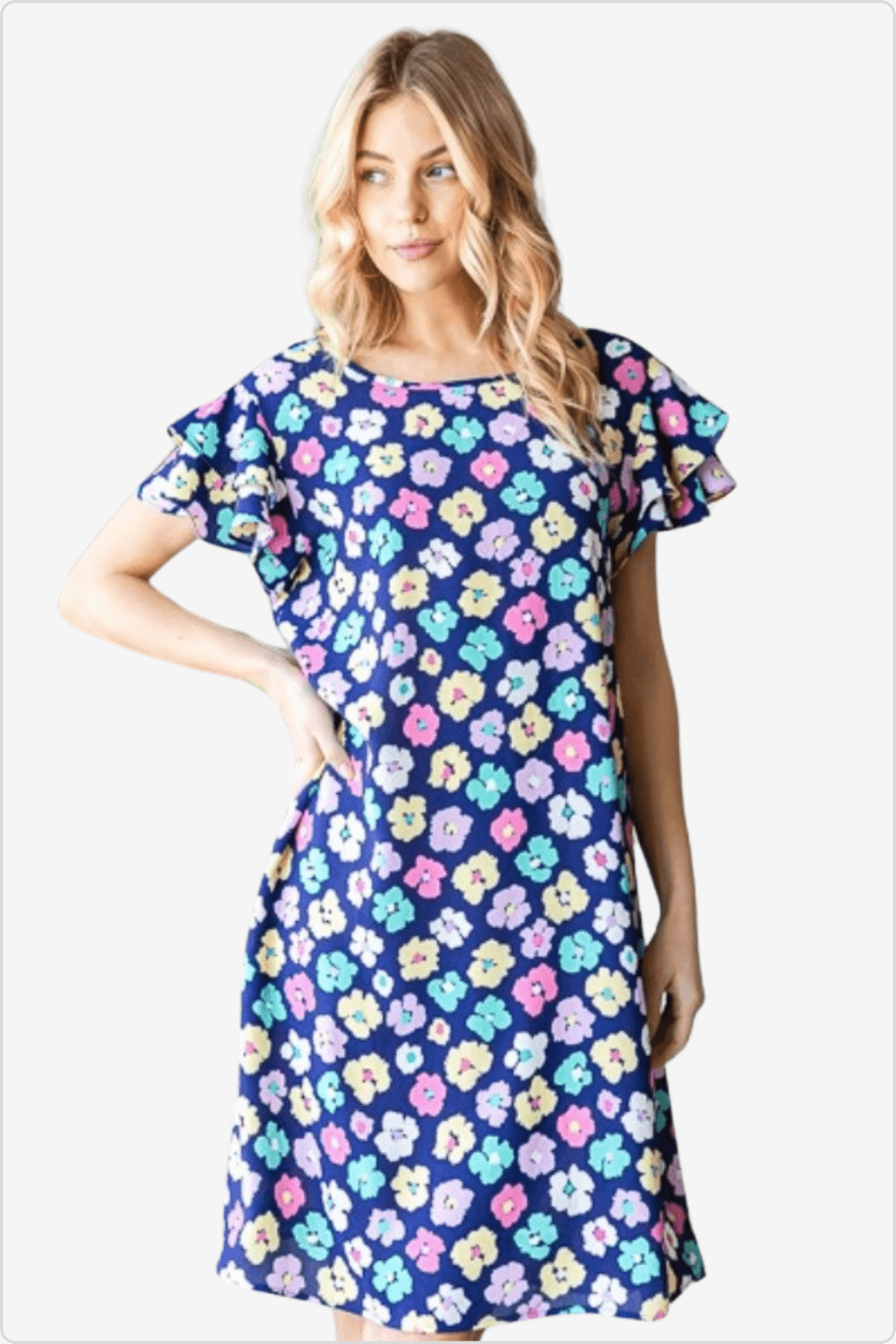 Fashionable short dress with bright multicolor floral pattern modeled by a woman with wavy blonde hair.