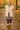 Model standing in autumn park in oatmeal quilted vest with diamond mini skirt and boots, golden leaves