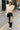 Model walking on city street in oatmeal quilted vest with patchwork jeans and white sneakers, autumn afternoon