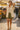 Woman walking through open market in oatmeal quilted vest with olive shorts, holding apple basket, sunny day