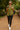 Woman in olive green shirt with jacquard hearts, black leggings and backpack, walking in park