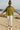 Woman in olive green shirt with jacquard hearts and white leggings, smiling on sandy beach