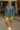 Woman in paisley denim shirt and lime bike shorts smiling at local street market