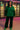 Front view of model in green hoodie with sequin sleeves and matching pants under neon light