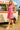 Holding ice cream in pink mini polo dress with espadrilles and orange earrings, fairground afternoon