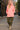 Walking in pink scuba hoodie with camo cargo pants and combat boots, urban alleyway, overcast