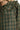 Close-up view of green plaid fabric showing ruffle collar trim and button stitching detail.