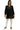 Model wearing black polka dot babydoll dress with plaid trim and ruffled hem, casual standing pose
