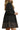 Side view of black polka dot babydoll dress with plaid trim and tiered hem, soft studio light