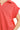 Close-up of coral red fabric with ribbed texture and polo neckline stitching