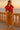Relaxing with drink in red polo sweatshirt, mustard culottes and sandals, ocean balcony, golden hour