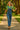 Walking in retro floral blouse with denim overalls and platform shoes, sunlit park path