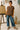 Woman standing in Oversized Crew Neck Sweater with clogs, near easel in studio, soft indoor light