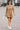 Female walking in ribbed long sleeve mini sweater dress latte with sneakers, urban street daylight.